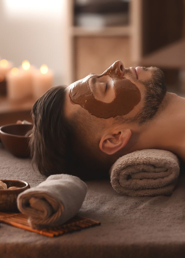 Client relaxing with a warm clay treatment mask applied to her face